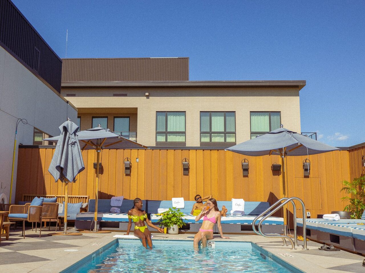 Two women sipping cocktails by the water at our Denver rooftop pool